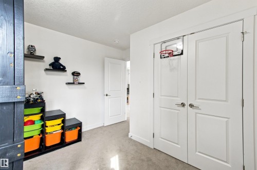 White interior walls, light neutral carpeting, white interior doors with contemporary hardware, and floating wall shelves - 107 Ellice Bend, Fort Saskatchewan, AB 