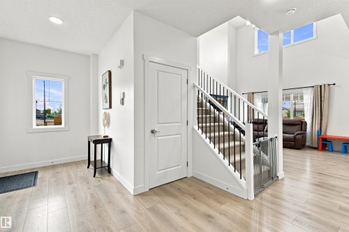 Two-story entry with wood-finish flooring, recessed lighting, and a window with white trim - 107 Ellice Bend, Fort Saskatchewan, AB 
