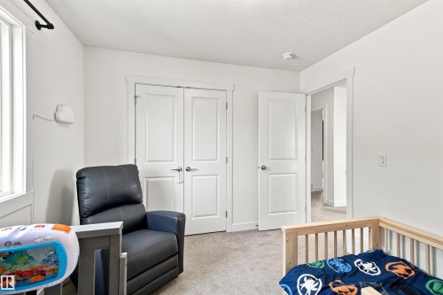 Neutral wall paint, white trim, carpet flooring, two-panel interior doors, and a window with a black rod - 107 Ellice Bend, Fort Saskatchewan, AB 