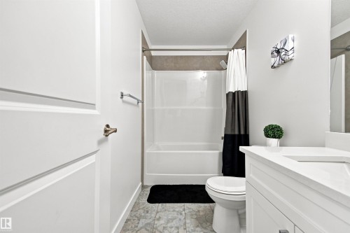 Bathroom featuring white cabinetry, a white vanity with an integrated sink, a white toilet, and a white shower-over-tub combination with tile surround - 107 Ellice Bend, Fort Saskatchewan, AB 