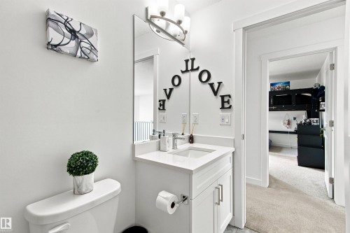 White vanity with a rectangular sink and a single-handle faucet, under a horizontal mirror with an overhead light fixture - 107 Ellice Bend, Fort Saskatchewan, AB 