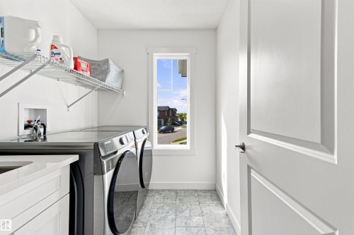 Laundry area featuring a window, white cabinetry, a built-in sink, and wire shelving - 107 Ellice Bend, Fort Saskatchewan, AB 