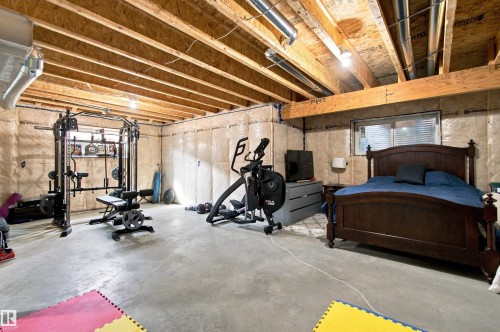 Versatile basement space featuring exposed beam ceiling with recessed lighting, polished concrete flooring, and flexible layout ideal for multi-purpose use - 107 Ellice Bend, Fort Saskatchewan, AB 