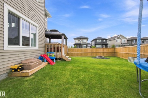 Expansive backyard featuring a manicured lawn, wood fencing, and a built-in fire pit - 107 Ellice Bend, Fort Saskatchewan, AB 