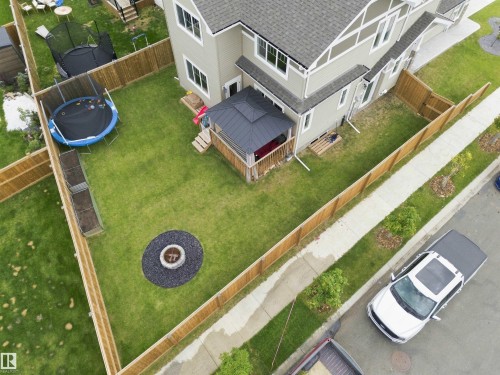 Manicured lawn with a built-in fire pit area and wood privacy fencing - 107 Ellice Bend, Fort Saskatchewan, AB 