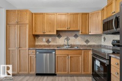 Kitchen featuring abundant wood-finish cabinetry, stainless steel appliances, a tile backsplash, and wood-finish flooring - 
