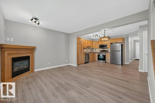 Wood-finish flooring throughout, featuring a gas fireplace with a wood mantel - #26 2816 34 Av Nw, Edmonton, AB 