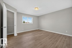 Wood-finish flooring, neutral gray walls, white trim, and a window with a natural light exposure - 