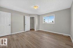 Spacious room featuring wood-finish flooring, light gray wall color, white trim, and a window with natural light - 