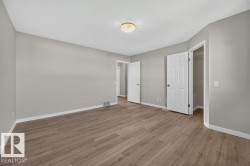 Spacious room featuring wood-finish flooring, light gray wall paint, white trim, and a flush mount light fixture - 