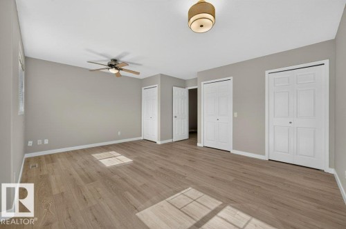 Wood-finish flooring, neutral wall tones, ceiling fan, flush mount lighting, and white bi-fold doors - #26 2816 34 Av Nw, Edmonton, AB 