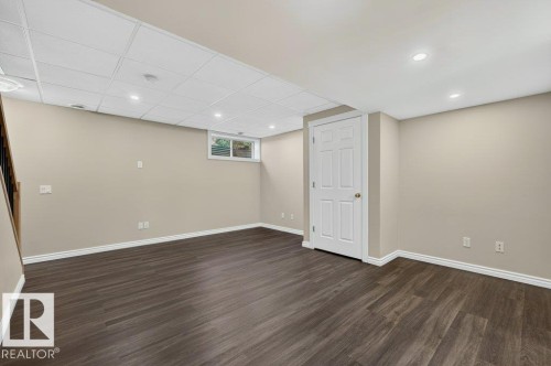 Finished basement featuring dark wood-finish flooring, recessed ceiling lights, and fresh neutral wall paint - #26 2816 34 Av Nw, Edmonton, AB 