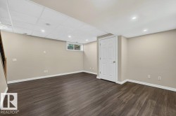 Finished basement featuring dark wood-finish flooring, recessed ceiling lights, and fresh neutral wall paint - 