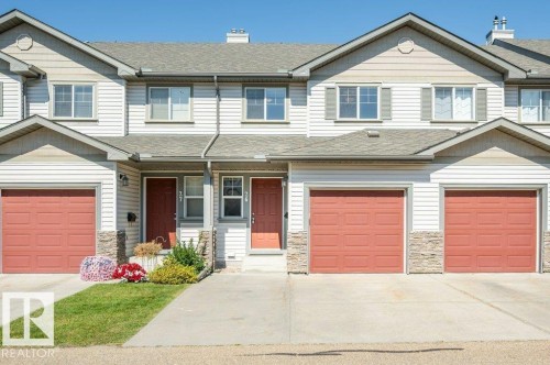 Vinyl siding exterior with a shingled roof, stone veneer accents, and multiple garage doors - #26 2816 34 Av Nw, Edmonton, AB 