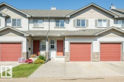 Vinyl siding exterior with a shingled roof, stone veneer accents, and multiple garage doors - 