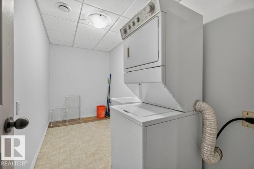 Dedicated laundry area featuring a stacked washer and dryer, utility sink, and tiled flooring - #26 2816 34 Av Nw, Edmonton, AB 