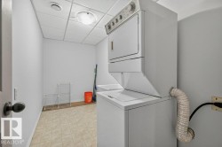 Dedicated laundry area featuring a stacked washer and dryer, utility sink, and tiled flooring - 