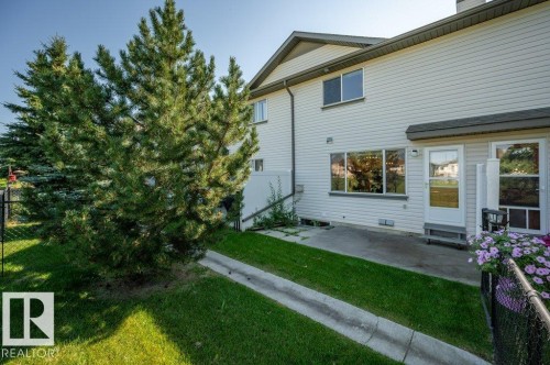 Exterior featuring horizontal siding, multiple windows, a rear entry door, and concrete patio - #26 2816 34 Av Nw, Edmonton, AB 