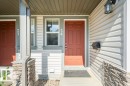 Entryway featuring a panel door, decorative outdoor lighting fixture, and stone veneer accents - #26 2816 34 Av Nw, Edmonton, AB 