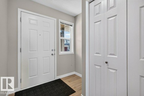 Entryway featuring a paneled door, wood-finish flooring, and a white framed window - #26 2816 34 Av Nw, Edmonton, AB 