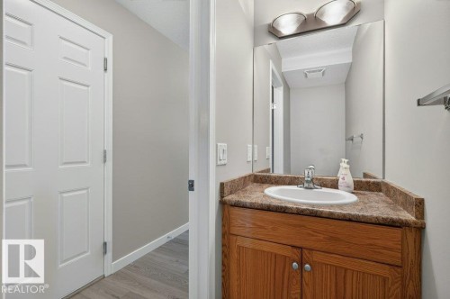 Wood-finish vanity with an integrated basin, a patterned countertop, and an overhead vanity light fixture - #26 2816 34 Av Nw, Edmonton, AB 