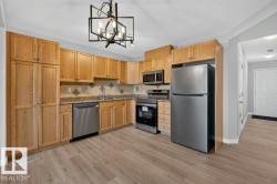 Kitchen featuring wood-finish cabinetry, stainless steel appliances, a mosaic tile backsplash, and wood-finish flooring - 