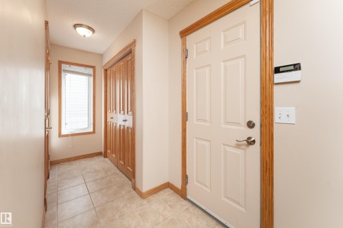 Entryway featuring tile flooring, a paneled door with brushed nickel hardware, and wood-finish trim - 10820 178 Avenue Nw, Edmonton, AB 