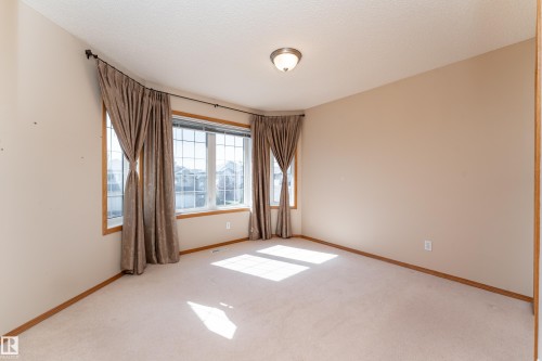 Light-colored carpeting with natural wood trim, a neutral painted wall, and a textured ceiling - 10820 178 Avenue Nw, Edmonton, AB 