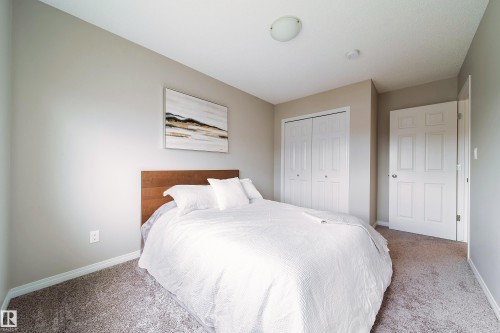 Neutral wall tones, textured carpet flooring, bi-fold closet doors, white paneled door, and a flush mount ceiling light - 3211 Cherry Crescent Sw, Edmonton, AB 