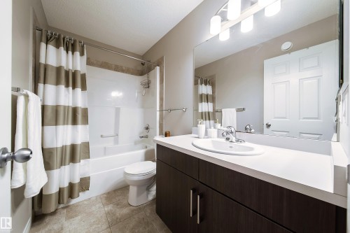 Full bathroom featuring a single vanity with wood-finish cabinetry and a white countertop, a drop-in sink, and a combination shower and tub - 3211 Cherry Crescent Sw, Edmonton, AB 