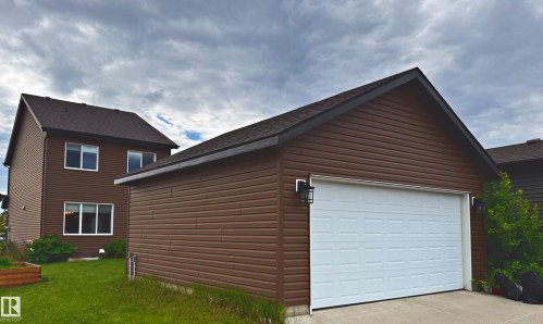 Brick and vinyl-sided two-story home with attached two-car garage featuring a white overhead door - 3211 Cherry Crescent Sw, Edmonton, AB 