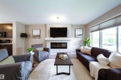 Spacious living area featuring a built-in fireplace, large windows, wood-finish flooring, and recessed lighting - 