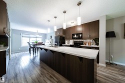 Kitchen featuring dark wood-finish cabinetry, white countertops, stainless steel sink, and pendant lighting - 
