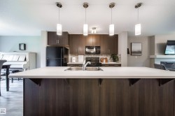 White countertop kitchen island with integrated stainless steel sink, dark wood-finish cabinetry, and stainless steel appliances - 