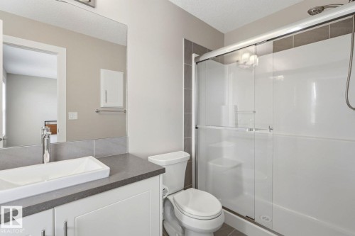 Contemporary bathroom featuring a white vanity with vessel sink, a gray countertop, and a shower with sliding glass doors - 206 Southfork Drive, Leduc, AB - Indoor Photo Showing Bathroom