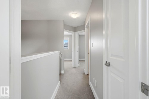 Upper-level hallway featuring neutral gray walls, light-colored carpeting, white trim, and white paneled doors with satin nickel hardware - 206 Southfork Drive, Leduc, AB - Indoor Photo Showing Other Room