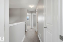 Upper-level hallway featuring neutral gray walls, light-colored carpeting, white trim, and white paneled doors with satin nickel hardware - 