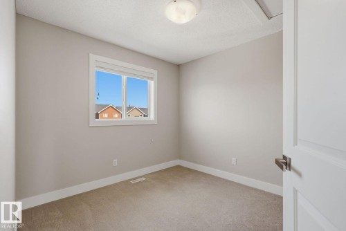 Neutral-toned room featuring a single window with white trim, light-colored carpeting, white baseboards, and a semi-flush ceiling light fixture - 206 Southfork Drive, Leduc, AB - Indoor Photo Showing Other Room