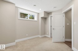 Carpeted room featuring neutral-toned walls, a white-trimmed window, and white interior doors with contemporary hardware - 