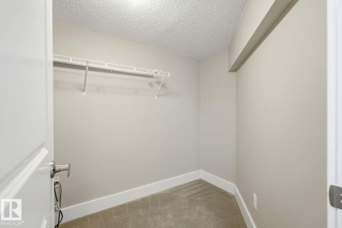 Walk-in closet featuring wire shelving, light neutral wall paint, white baseboards, and carpet flooring - 206 Southfork Drive, Leduc, AB - Indoor With Storage