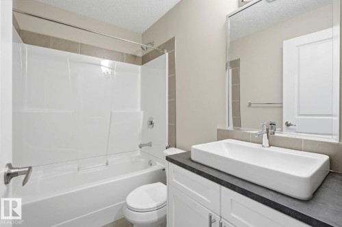Modern bathroom featuring a rectangular vessel sink, dark countertop, and white cabinetry - 206 Southfork Drive, Leduc, AB - Indoor Photo Showing Bathroom