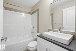 Modern bathroom featuring a rectangular vessel sink, dark countertop, and white cabinetry - 