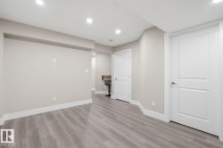 Open-concept interior featuring wood-finish flooring, recessed lighting, neutral wall tones, and white trim - 