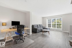 Living area featuring wood-finish flooring, neutral wall tones, and a large window with white blinds - 