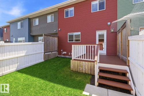 Expansive backyard featuring a lush green lawn, a multi-level deck with steps, and a white picket fence - 206 Southfork Drive, Leduc, AB - Outdoor With Deck Patio Veranda With Exterior
