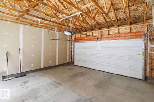 Spacious two-car garage with unfinished drywall, concrete flooring, and exposed wood ceiling trusses - 206 Southfork Drive, Leduc, AB - Indoor Photo Showing Garage