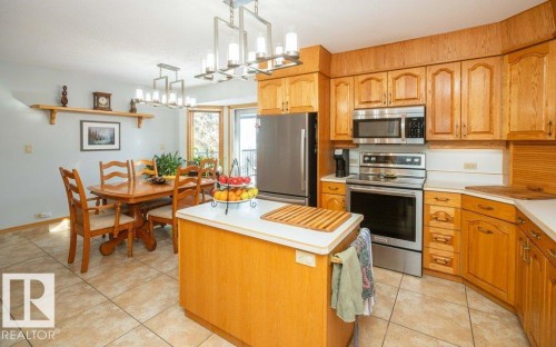 Kitchen with wood cabinetry, stainless steel appliances, and a central island with a solid surface countertop - 11007 108 Avenue, Westlock, AB 