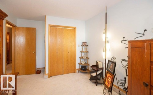 Spacious upper-level room featuring warm wood-finish closet doors, neutral carpet flooring, and abundant natural light from recessed ceiling fixtures - 11007 108 Avenue, Westlock, AB 