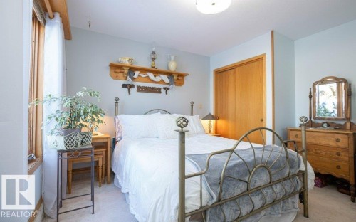 Room with light blue walls, wood-trimmed window, wood-finish bi-fold closet doors, and light-colored carpet - 11007 108 Avenue, Westlock, AB 