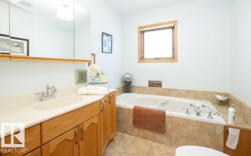 Integrated bathtub with tiled surround, wood-finish vanity with counter, and recessed medicine cabinet - 11007 108 Avenue, Westlock, AB 